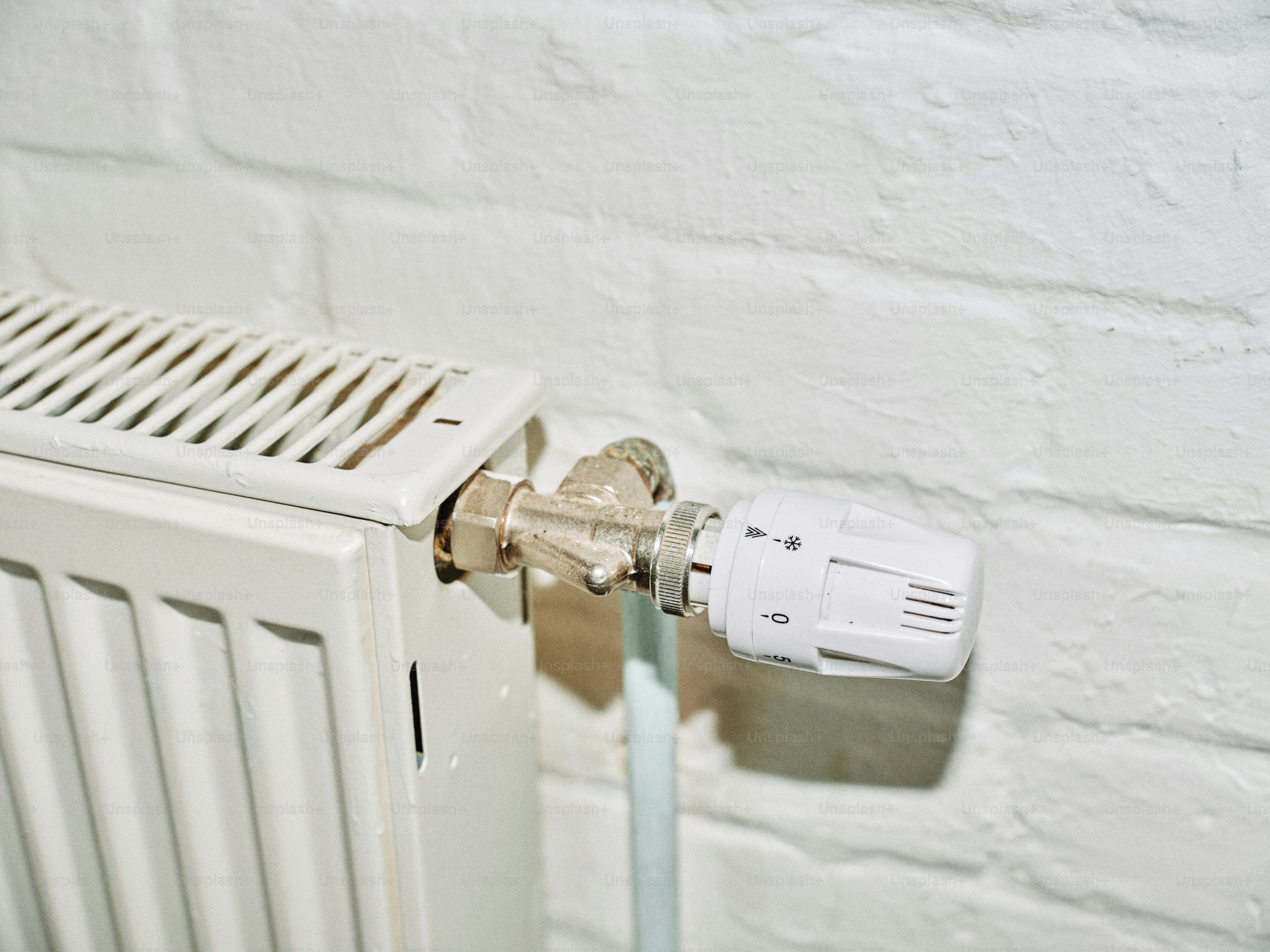 Radiator valve next to a white brick wall